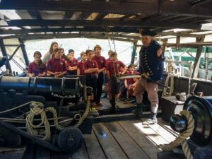 Image of school kids aboard the Philadelphia 2 with an historic 1776 era interpreter