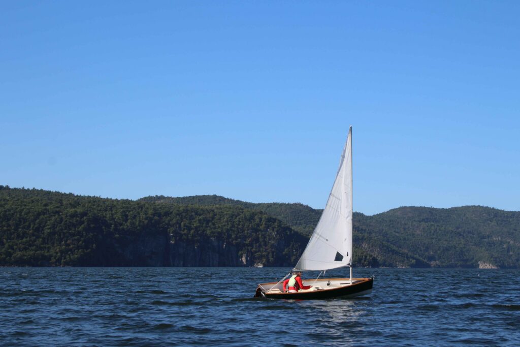 09112026-Sailing_KJLN.003 lowres A sailboat in front of green mountains and a blue sky