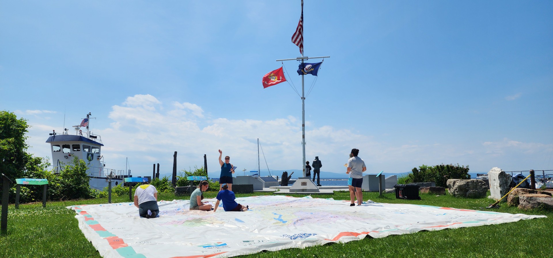 A giant map spread out on a lawn under a blue sky