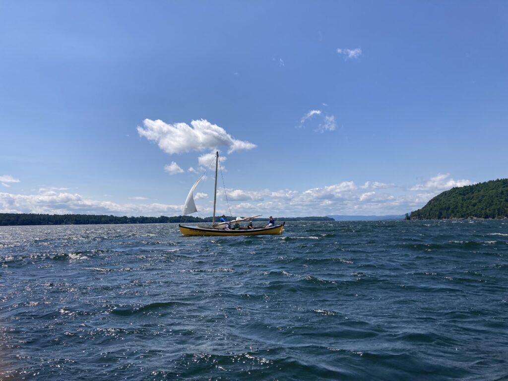 A yellow sailboat on a windy lake.