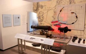An exhibit showing an exploding cannon with a large map behind.